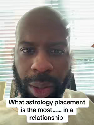 A close-up shot of a Black man's face filling the frame. He has a shaved head and a full, neatly trimmed beard. The background is slightly out of focus but appears to be an interior with blinds. At the bottom, a white text overlay states the video's topic relating it to astrology and relationships.