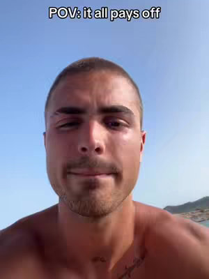 A selfie image of a man with a shaved head is shown, the top half of his body is shown and his upper body is bare, the sky is in the background.