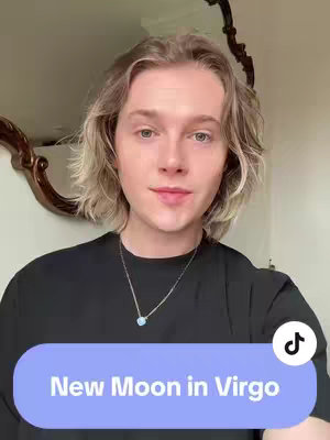 A young person with blond hair, wearing a black top and a necklace, is positioned in front of what appears to be a mirror and a wall. A colored bar with the text "New Moon in Virgo" can be seen at the bottom of the image. The tiktok logo is visible too.