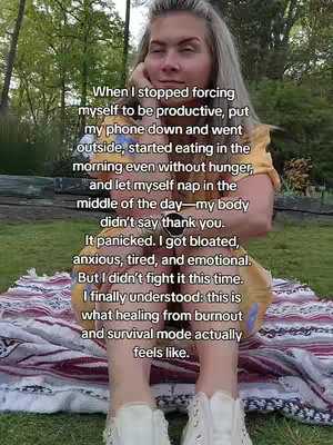 A woman with blonde hair in a yellow top is sitting. The image is taken from the waist up. The woman is sitting on a blanket in a grassy area with trees in the background. Text is overlayed on the image.