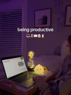 The cover image shows a person's hand typing on a opened laptop keyboard, lit up by a desk lamp and a glowing decorative light with a cozy bedroom background, and a banner above that says 'being productive' with emojis.