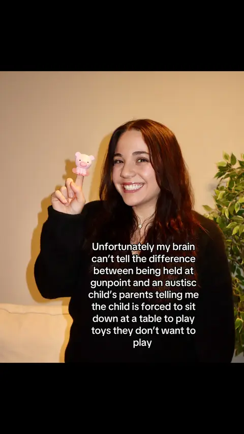 A woman with long brown hair is smiling directly at the camera while holding a small pink pig figurine on her index finger; text is overlaid at the bottom right.