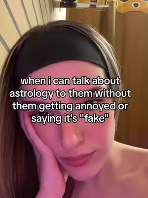 A close-up image shows a person's face, likely a selfie, with the person's right hand gently placed on the cheek near their mouth, suggesting a thoughtful or emotional expression. The person has light skin, dark hair styled with a headband, and visible dark eye makeup and lipstick. Overlaid text in a white, sans-serif font presents a conversation opener about astrology, highlighting a relatable issue related to the subject.