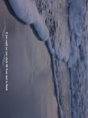 The image shows an abstract view of water on a surface, possibly a wave, with a vertical text overlay. Shades of blue and white dominate the image, creating a sense of depth and movement. The background is hazy, while the foreground features textured water creating a pattern of white foam and streaks against the darker blue. The text is vertically aligned on the left side of the image, in a white font.