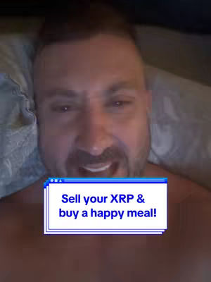 A close-up shot of a man's face, with a white text box overlaid on his chest against a background of a blurred room. The man has short hair, a beard, and is looking toward the viewer. He is wearing nothing. The background is out of focus, with dim lighting. There is a text box in the lower center with text.