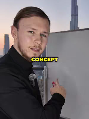 A well-lit shot features a man in a black collared shirt with a blurry cityscape background, primarily featuring a large skyscraper. The man is positioned slightly off-center, with half of his body facing the camera. He has light-colored hair styled neatly, suggesting a professional appearance. The text 'CONCEPT' in a yellow box is positioned at the bottom, left of the screen. The man is pointing towards an imaginary object, towards a large whiteboard, and he appears to be addressing the camera, likely explaining a concept.
