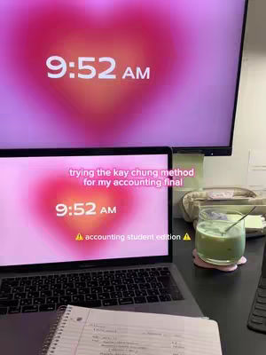 A laptop and a larger monitor show a heart-shaped gradient in the background. Text overlayed on the laptop screen includes, 'trying the kay chung method for my accounting final' and 'accounting student edition'. A glass of green beverage is on the right.