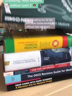 A stack of medical textbooks is shown, with the focus on the spines that have text. The top part shows some text overlay indicating unboxing of the material, the background is blurry and shows the rest of the books.