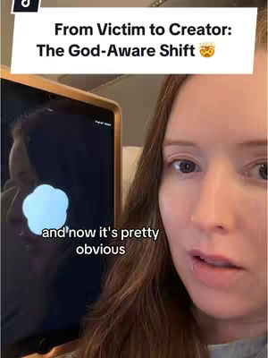 A woman with long brown hair looks at the camera with a questioning expression. She is positioned to the right of the frame. To the left, a screen displays an abstract bright shape reflecting on her face. The background suggests an indoor setting, potentially an office.