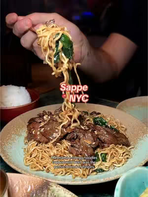 The cover image shows a plate of Thai food with noodles, beef, and greens being lifted with chopsticks. The background includes a bowl of white rice, and a hand is visible holding up the food.