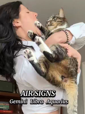 A woman holds a cat close to her face in a loving pose, with both appearing to interact playfully. Text overlayed at the bottom identifies the zodiac signs. The background hints at an indoor setting.