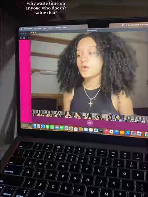 A laptop displaying a video recording of a young woman, with text overlayed. The laptop keyboard is visible in the foreground.