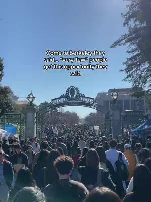 A wide shot captures a bustling crowd gathered behind a decorative iron gate, likely at a university entrance. The image is filled with people, and the background includes trees and buildings under a clear, bright blue sky. Overlay text at the top reads 'Come to Berkeley they said... "very few" people get this opportunity they said'.