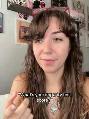 A woman with long brown hair and bangs is smiling at the camera, a text overlay appears at the bottom that reads, "What's your impurity test score?" The background shows a room decorated with artwork.