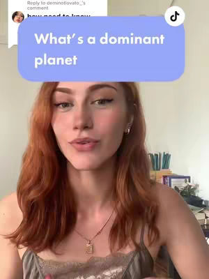 A woman with auburn hair is centered in the shot. She’s wearing a gray top and a necklace. Behind her is a neutral background with some stationery, and there’s a text overlay above her head.
