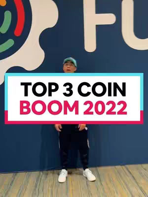 A man in a blue cap and sportswear stands in front of a dark blue wall with white artistic shapes. A text overlay in a rectangular, color-blocked design says 'TOP 3 COIN BOOM 2022'.