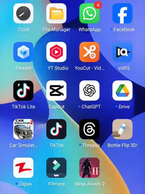 The image is a screenshot of a smartphone's home screen. The screen displays a grid of app icons against a blue, subtly patterned wallpaper. Applications are organized in rows and columns, and include popular apps indicated by their logos, such as TikTok, WhatsApp, YouTube Studio, and others. The layout provides a clear view of various app icons, with a clean and organized look.