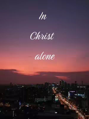 The image is a nighttime cityscape with a dark purple and orange gradient sky. The city is silhouetted in the lower portion of the image, with lights creating a sense of activity. Text overlayed in the center of the frame reads 'In Christ alone'.