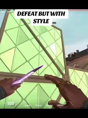 A first-person view from a video game, showing a hand holding a purple knife in front of a wall made of green glass panels. The person has rings on their fingers.