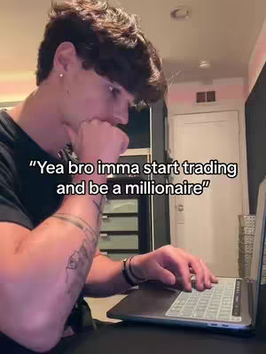 A young man is sitting at a desk with a laptop, looking thoughtful. The image has a medium shot, and the man is positioned slightly to the left. He is wearing a black t-shirt and has short, dark hair. A tattoo is visible on his left arm. The background is blurred, but suggests a room with a door and a pink wall. A text overlay at the bottom reads 'Yea bro imma start trading and be a millionaire'.