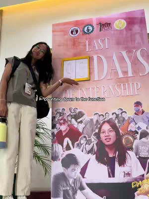 The cover image features a young woman in a casual outfit, standing next to a large poster. The poster has "LAST DAYS OF INTERNSHIP" written on it. The woman is smiling and pointing at the poster. There is a text overlay at the top of the image that reads "counting down to the function". The background appears to be an office space.
