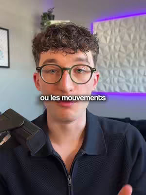 A man with glasses is centered in the frame, looking towards the viewer. Text reading "ou les mouvements" is superimposed on his mouth, suggesting a focus on the question being asked. The background is softly blurred with a patterned wall and purple lighting.