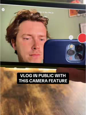 The cover image shows a man holding a phone in front of his face as if recording a video. The top part of the screen displays a green wall with some pictures, the creator of the video, with brown hair and red hair is visible. A black rectangle with white text overlay saying "VLOG IN PUBLIC WITH THIS CAMERA FEATURE".