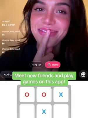 A selfie-style video cover shows a young woman with brown hair smiling and pointing a finger to her lips, with a gaming app interface in the background.