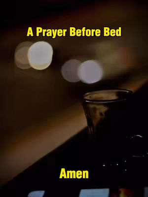 The image is dark, with blurred background lights. In the foreground is a glass, and the text 'A Prayer Before Bed' is written in a yellow font at the top. The word 'Amen' also written at the bottom.