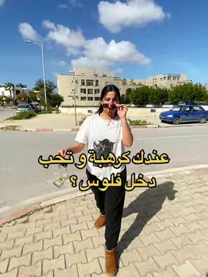 A woman in a white t-shirt and black pants is walking on a brick road on a sunny day. She's holding sunglasses and there's text overlayed on the image, with a car in the background.