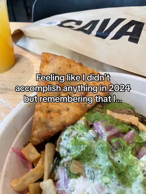 The image shows a CAVA takeout bowl with a pita chip and a glass of orange juice, setting the scene as casual dining and food.