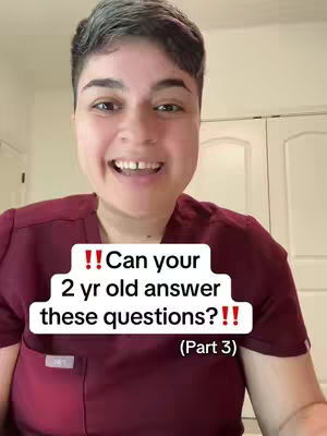 A woman with short, gray hair smiles directly at the camera. She's wearing a maroon top and the background shows a plain wall and a glimpse of a white cabinet. White text overlaying the image poses a question about toddlers.