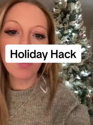 A woman's face is centered, partially obscuring a tree on the right. A white rectangle with the text reads "Holiday Hack" overlays her face. She is wearing a gray sweater and a necklace.