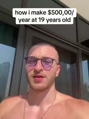 A man with short, dark hair and glasses is looking directly at the camera. Overlay text says, "how i make $500,00/ year at 19 years old". The background appears to be a bright outdoor setting with a glass door.