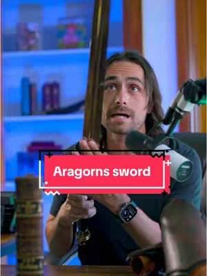 A man with medium-length brown hair is holding a sword in front of a bookshelf. He is looking up, and there is a red text overlay on the cover image that reads "Aragorns sword". A microphone is set up in front of him.