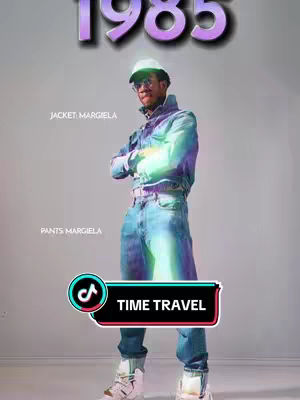 A man stands in a studio setting, wearing a denim jacket and jeans, a white cap, and glasses. The image has a futuristic or stylized aesthetic. Text overlays indicate "1985" and mentions "JACKET: MARGIELA" and "PANTS MARGIELA". A TikTok logo with "TIME TRAVEL" is placed at the bottom.