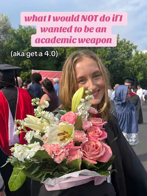 A young woman smiles, holding a bouquet of pink and white flowers, positioned in front of her. She wears a dark top, and a pink rectangular text overlay at the top, which states "what I would NOT do if I wanted to be an academic weapon (aka get a 4.0)". There are other blurred people in the background, and general outdoor setting.