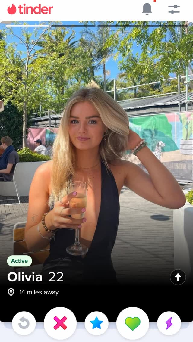 The cover image shows a woman using a dating app. The woman is blonde, holding a glass of champagne. The background shows an outdoor setting with foliage and a blurred background. The interface indicates its the dating app Tinder, with the woman's profile displayed and the standard app interface buttons.