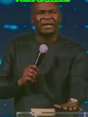 A man speaking into a microphone in front of a blurred background with the text "Power of decision" overlaid on the image. The man is wearing a dark, long-sleeved shirt and has a watch on his wrist. The pose is animated.