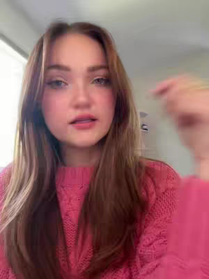 The cover image features a young woman with long, light brown hair and a pink sweater, looking directly at the camera. The background is blurred, and the lighting appears to be soft. She is pointing with her right hand, and her expression is neutral.
