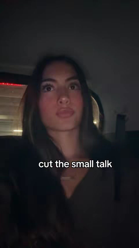 A woman is captured in a selfie-style shot, seated inside a vehicle, possibly a car, with a blurred background. The primary focus is on her face expressing. Overlaid at the bottom is the text 'cut the small talk'.