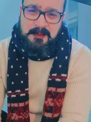 The cover image shows a man with glasses, a mustache and a full beard wearing a cream sweater and a scarf. The scarf is navy blue with white polka dots and a pattern of red and white. The man has glasses and looks directly at the camera.