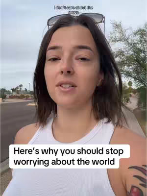 A woman is standing outdoors, facing the camera. She is wearing a white tank top and sunglasses are perched on her head. Text overlays appear at the top and bottom of the image. The woman has dark hair and a casual expression. The background shows a residential street with greenery and a cloudy sky.