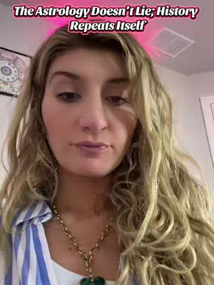 A selfie-style video cover image features a woman with blonde wavy hair against a soft-lit background. Above her is text in a pinkish hue that reads, 'The Astrology Doesn't Lie; History Repeats Itself.' She wears a white top, a striped shirt, and a gold necklace.