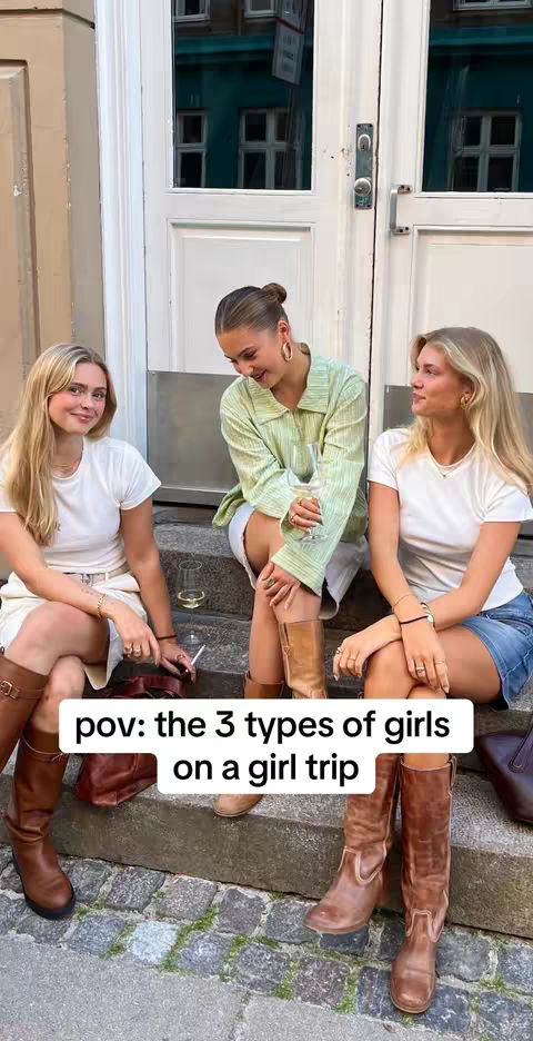Three young women are seated on steps outside a building. One is in a light green shirt and has her hair pulled back, the other two are wearing white t-shirts. The women appear to be enjoying a day out.