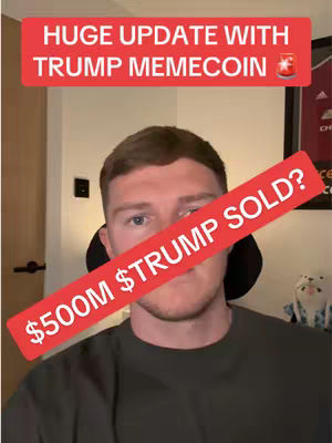 A man with light skin and short brown hair is centered in the frame, set against a blurred room background. He wears a dark green shirt. A red banner overlaid diagonally across his face displays the text '$500M Trump Sold?', the text in white. Above him, a red rectangular banner reads 'HUGE UPDATE WITH TRUMP MEMECOIN' in white font, with a small icon on the right, likely an image inside a circle. The image color scheme is primarily neutral and the lighting appears to be from the front.