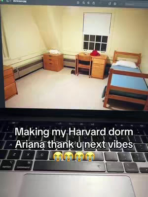 The picture shows a room inside a Harvard dorm. It features a wide window, a bed, a desk, and a radiator. A laptop in the foreground is on top of a keyboard with the text overlayed. The composition is simple, with a focus on the room's interior.
