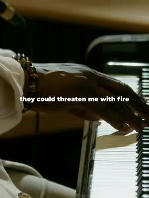 A close-up shot of a hand with a beaded bracelet playing a piano, with overlayed text.