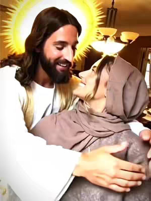 A warm, slightly blurred image depicts a close embrace between two figures. The figure on the left, presumably Jesus, has long brown hair, a beard, and a radiant halo. He wears a white robe and smiles lovingly at the embraced individual, who is veiled and clad in a brown cloth, looking up with a smiling expression. They are in a room with warm lighting.