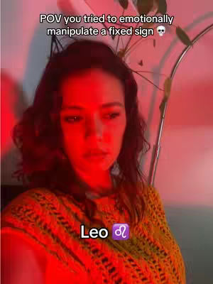 A woman with dark hair and a yellow sweater is centered in a cover image. The lighting is predominantly red, creating a warm, but intense atmosphere. Text overlay indicates a meme-like astrology theme.